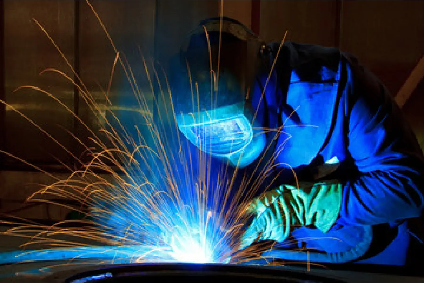A MIG welder working on a table with sparks flying